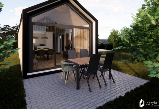 Udendørs spiseområde foran Reestdal lodge med store vinduer på Camping Si-Es-An i Holland, omgivet af træer.