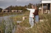 Twee mensen genieten bij het water van het uitzicht bij Water lodge 2 + hot tub, tussen natuur en lodges.