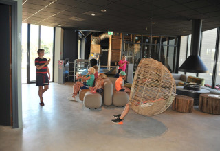 Kinderen ontspannen en spelen in de moderne lounge van Zonneweelde Lodge Deluxe op Camping Zonneweelde.