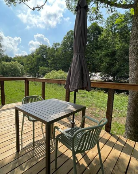 Terrasse mit Tisch, zwei Stühlen und geschlossenem Sonnenschirm im Hameau de la Semois, Belgien Luxemburg.