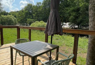 Terrasse mit Tisch, zwei Stühlen und geschlossenem Sonnenschirm im Hameau de la Semois, Belgien Luxemburg.