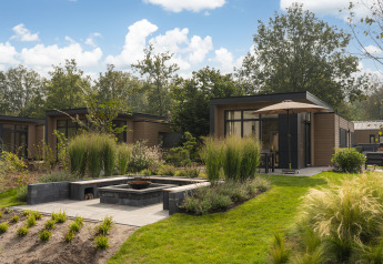 Moderne Cannenburch Deluxe met Hottub Lodge mit Terrasse, Garten und stilvollem Außenbereich bei Sonnenschein.