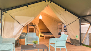 Interior of a safari tent with modern furnishings and private toilet at Vestbirk Camping, Denmark.
