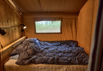 Interior de una tienda safari en Vestbirk Camping, Dinamarca, con cama doble y lámparas de lectura.