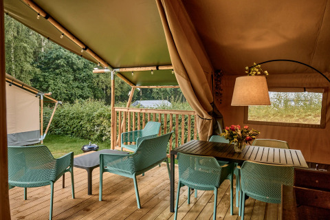 Safari-Zelt mit modernen sanitären Einrichtungen und Terrasse auf Vestbirk Camping in Dänemark, umgeben von Natur.