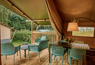 Tenda safari con servizi igienici moderni e terrazza al Vestbirk Camping in Danimarca, circondata dal verde.