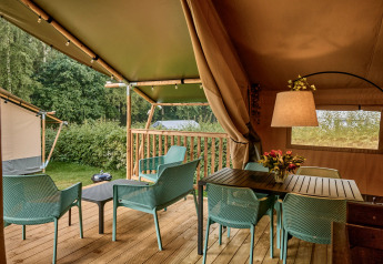 Tienda safari con instalaciones sanitarias modernas y terraza en Vestbirk Camping, Dinamarca, con vegetación.