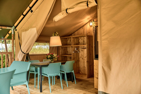 Interno di una tenda safari con zona pranzo e comfort moderni a Vestbirk Camping in Danimarca.