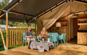 Couple relaxing at a safari tent with sanitary facilities at Vestbirk Camping in Denmark.