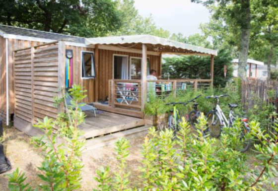Mobil-home en bois premium au Flower Camping La Canadienne en France, avec terrasse et vélos devant.