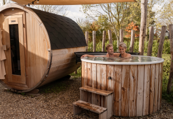 Stel geniet van een hottub en sauna buiten bij Water lodge 6 Deluxe, omringd door houten hekwerk.