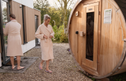 Twee mensen in badjassen bij een tonvormige sauna bij Water Lodge 6 Deluxe, Hofparken Wiltershaar.
