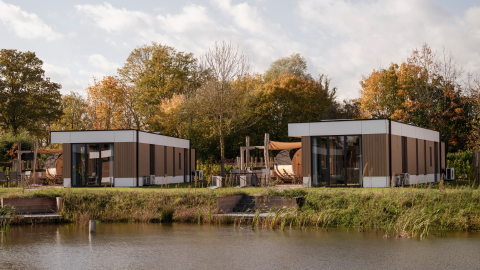 Modern water lodge by a lake at Hofparken Wiltershaar in the Netherlands, surrounded by autumn trees.