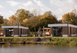 Lodge moderne au bord de l'eau à Hofparken Wiltershaar, Pays-Bas, entouré d’arbres aux couleurs d’automne.