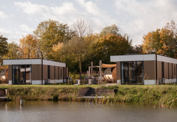 Lodge moderne au bord de l'eau à Hofparken Wiltershaar, Pays-Bas, entouré d’arbres aux couleurs d’automne.
