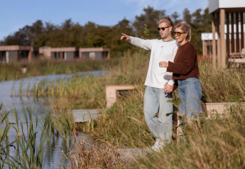 Twee personen aan het meer bij Water lodge 6 Deluxe, Hofparken Wiltershaar, Nederland, ontspannen in de natuur.