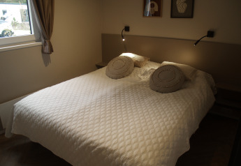 Cozy lodge bedroom with a double bed, quilted white bedding, round pillows, and soft wall lighting.