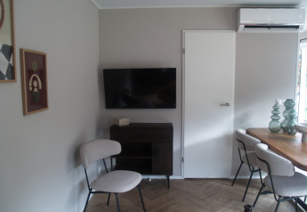 Salon moderne dans Groeneborg lodge avec TV, coin repas et climatisation à Vakantiepark De Wiltzangh.