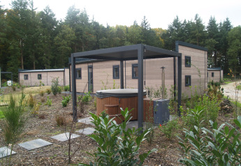 Groeneborg Lodge with hot tub at Vakantiepark De Wiltzangh in the Netherlands, surrounded by greenery.