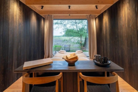 Interiør af Nokken Forest Cabin ved Wilsumer Berge, Tyskland, med udsigt til naturen gennem stor rude.