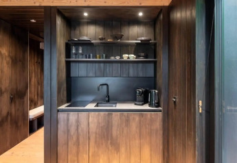 Moderne Küchenzeile in der Nokken Forest Cabin in Wilsumer Berge, Deutschland, mit dunklen Holzpaneelen.