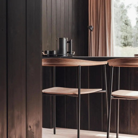 Interno moderno della Nokken Forest Cabin con sedie in legno e vista sul bosco a Wilsumer Berge, Germania.