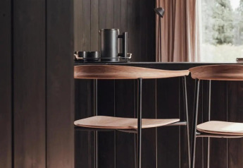 Moderne interiør af Nokken Forest Cabin med mørke vægge, træstole og udsigt til skov i Wilsumer Berge.