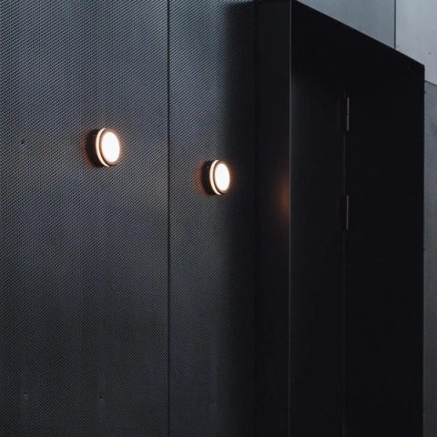 Rivestimento murale nero moderno e applique rotonde nel Nokken Forest Cabin a Wilsumer Berge, Germania.