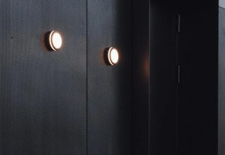 Moderne sorte vægbeklædninger og runde væglamper i Nokken Forest Cabin ved Wilsumer Berge, Tyskland.