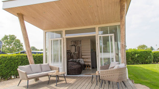 Comfortabele zitruimte buiten aan Beach Loft tiny house bij Camping Zonneweelde, Nederland.