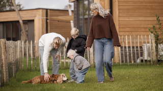 Gezin met twee kinderen en hond speelt buiten aan Parklodge 6 met hondenhek, sauna en hottub.