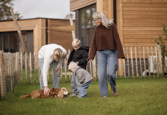 Familia con dos niños y un perro disfruta al aire libre en Parklodge 6 con valla, sauna y jacuzzi.
