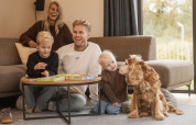 Famille réunie dans un lodge, jouant à un jeu de société avec leurs enfants et leur chien.