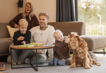 Famille réunie dans un lodge, jouant à un jeu de société avec leurs enfants et leur chien.