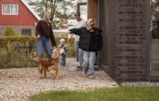 Familia disfruta al aire libre en un lodge, niños y perro juegan juntos en el sendero de grava.