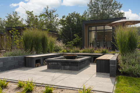 Gemütlicher Gartenbereich mit Feuerstelle vor einer modernen Lodge im Cannenburch Deluxe met Hottub, Veluwepark de Bosgraaf.