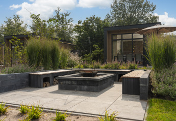 Gemütlicher Gartenbereich mit Feuerstelle vor einer modernen Lodge im Cannenburch Deluxe met Hottub, Veluwepark de Bosgraaf.