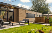 Außenbereich der Cannenburch Deluxe Lodge mit Whirlpool und Gartenmöbeln im Veluwepark de Bosgraaf.