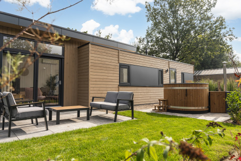 Außenbereich der Cannenburch Deluxe Lodge mit Whirlpool und Gartenmöbeln im Veluwepark de Bosgraaf.