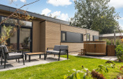 Outdoor area of Cannenburch Deluxe lodge with hot tub and garden furniture at Veluwepark de Bosgraaf, NL.