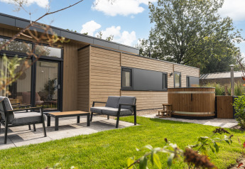 Outdoor area of Cannenburch Deluxe lodge with hot tub and garden furniture at Veluwepark de Bosgraaf, NL.