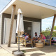 Familie sidder udenfor en moderne lodge ved Camping Zonneweelde, Beach Loft, i Holland, og hygger sig.
