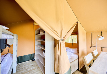 Vista interna di una tenda safari Compact con letti a castello, scaffali e tavolo al Camping de Molenhoek.