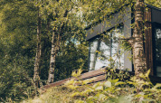 De Nokken NKN-18 Cabin in Wilsumer Berge, Duitsland, omringd door bomen, gras en wilde bloemen.