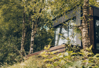 Nokken NKN-18 Cabin at Wilsumer Berge, Germany, nestled among lush trees, grass, and wildflowers.