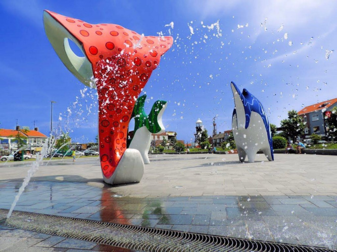 Esculturas coloridas de delfines y fuentes de agua en el área de juegos de un camping glamping.