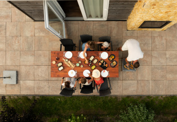 Aerial view of a family dining outdoors at a wooden table at Resort Mooi Bemelen in the Netherlands.