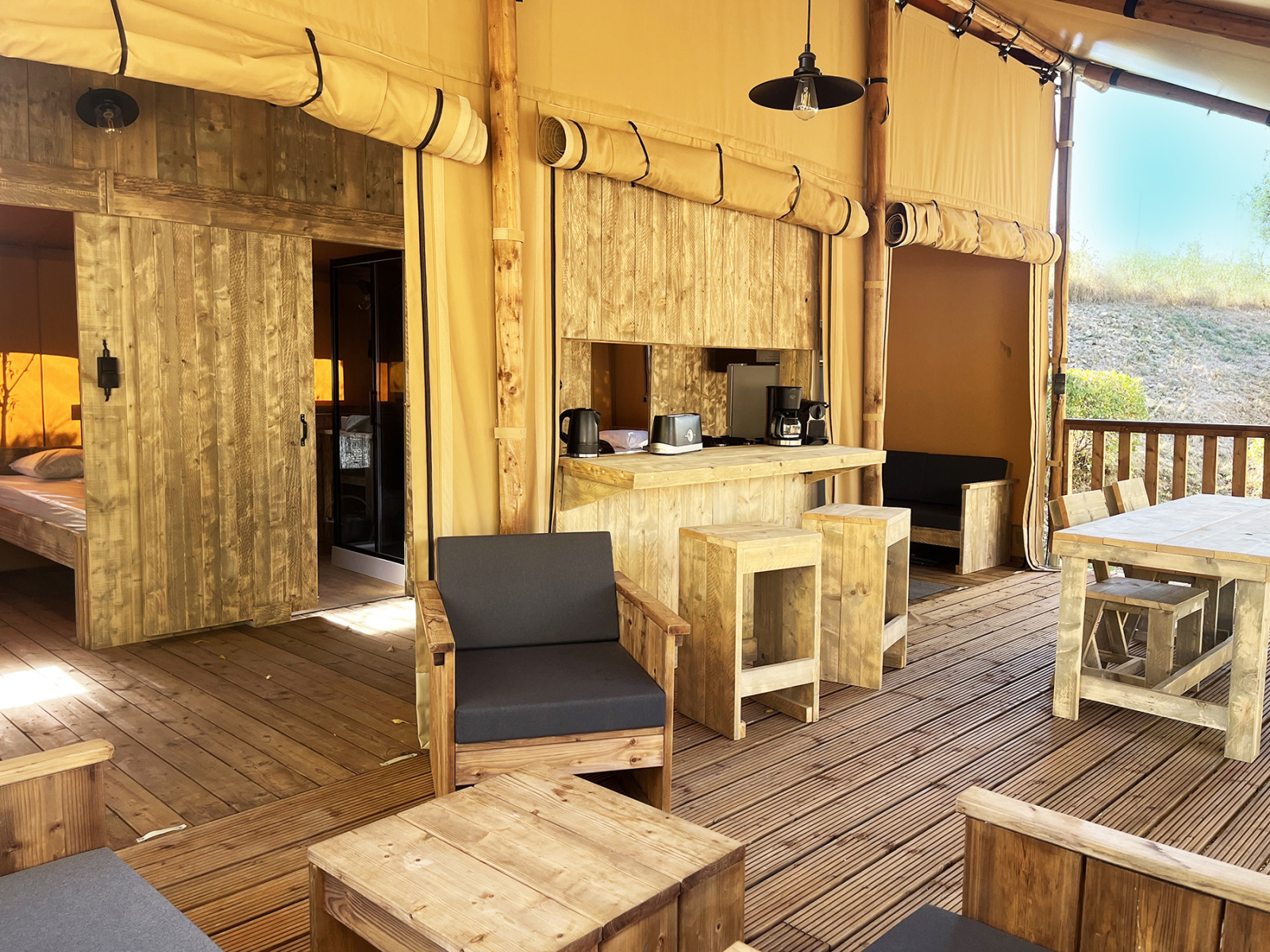 Interieur van een luxe safari glamping lodge met houten meubilair op Camping Le Val de Cesse, Frankrijk.
