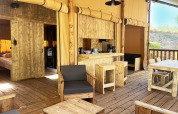 Indvendigt billede af en luksuriøs safari glamping lodge med træmøbler på Camping Le Val de Cesse, Frankrig.