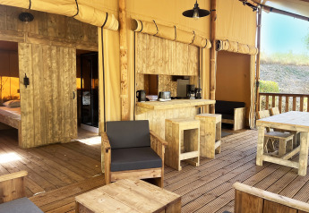Interno di una tenda safari glamping premium con arredi in legno al campeggio Le Val de Cesse, Francia.